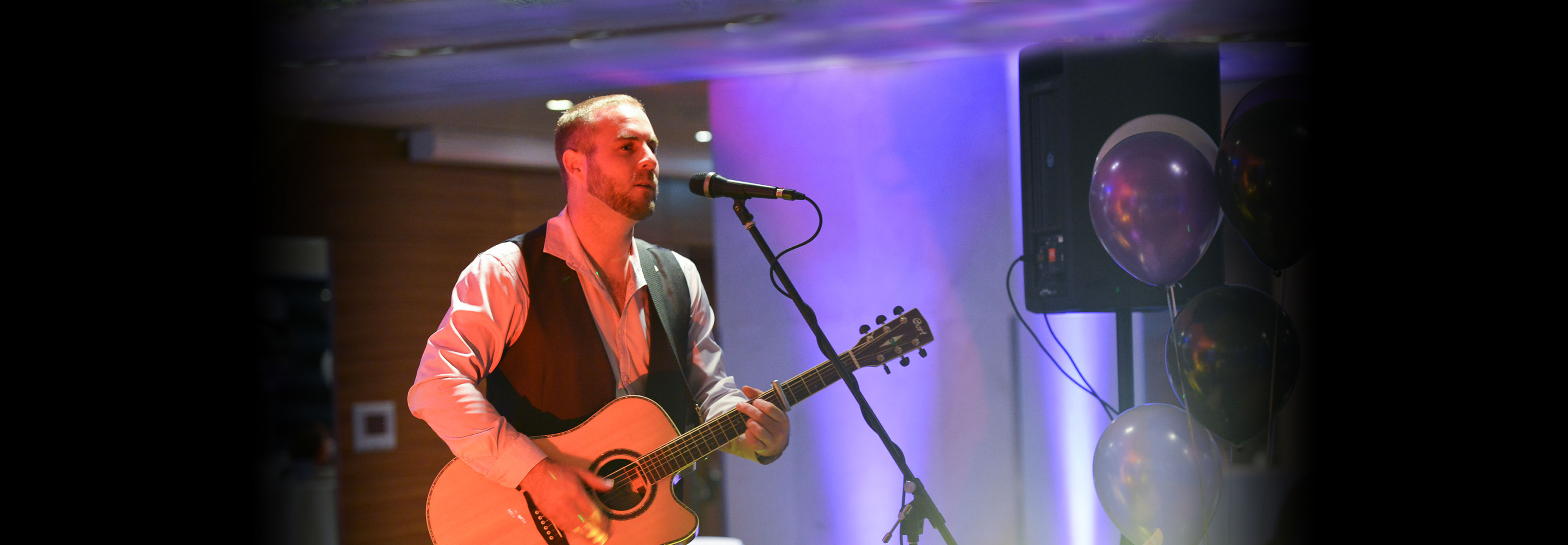 Chris performing on stage with an acoustic guitar